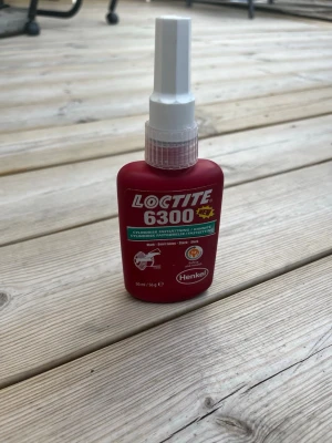 Loctite 6300 lim 50 ml - Röd flaska med vitt lock innehållande Loctite 6300, ett lim för fastsättning av cylindriska delar. Flaskan rymmer 50 ml och är märkt med Henkel. Perfekt för verkstadsjobb och hobbyprojekt där stark fixering behövs.