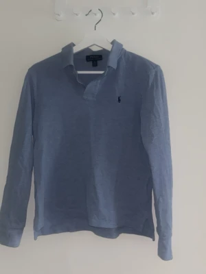 Polo Ralph Lauren ljusblå skjorta 14-16 L - Ljusblå långärmad skjorta från Polo Ralph Lauren i mjuk bomull. Klassisk krage och liten broderad logga på bröstet. Enkel och stilren design som funkar till det mesta.