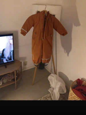 Orange täckoverall med fuskpäls - This is an kids overall it’s in good condition but has been worn alot of times. The size is:86cm. BEFORE YOU BUY THIS IS MEANT FOR KIDS/TODDLERS. I put no size on down in size because they wouldn’t show me and option for baby sizes