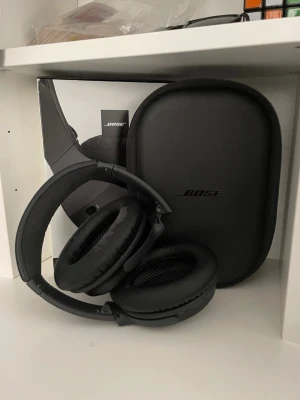 Bose QuietComfort 35 II hörlurar - Säljer ett par svarta Bose QuietComfort 35 II over-ear hörlurar. De är trådlösa och har brusreducering. Medföljer originalfodral, laddkabel och ljudkabel. Hörlurarna har en stilren design i plast och konstläder, perfekta för musik, gaming eller resor.