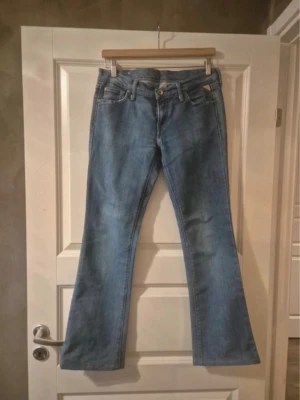 Ljusblåa Replay jeans low waist - Säljer ett par ljusblå replay bootcut jeans med klassisk femficksmodell och gylf med knapp. Jeansen har en lätt utsvängd passform nedtill och är tillverkade i denim. W29 L32