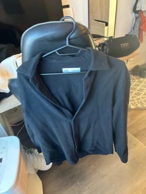 Svart långärmad skjorta från Zara - Stilren svart skjorta från Zara med klassisk krage och lång ärm. Skjortan har en enkel och clean look, perfekt för dig som gillar minimalistisk stil. Tillverkad i mjukt material som känns skönt mot huden.