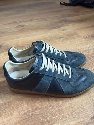 Maison margiela gats - Snygga sneakers i blå mocka och textil med vita skosnören och klassisk gummisula. Skorna har en låg profil och retroinspirerad design som passar perfekt till jeans eller streetwear. Tidlös look med kontrasterande material och diskreta detaljer.