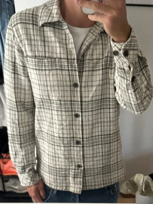  overshirt - Rutig overhsirt från Samsoe samsoe. Skjortkrage och långa ärmar med knapp vid ärmslut. Tillverkad i ett mjukt tyg som ger en avslappnad look. Perfekt att bära över en t-shirt för en casual stil. Den ena knappen på ena armen saknas men annars My let bra skick 