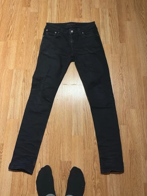 Svarta nudie - Säljer ett par svarta avslappnade jeans med klassisk femficksdesign och smal passform. Jeansen har dragkedjegylf och raka ben. Perfekta för dig som gillar en stilren och avslappnad look. Pris kan diskuteras 