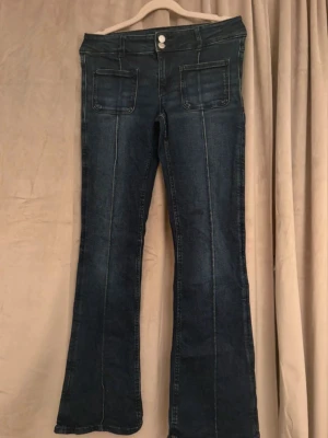 Mörkblå bootcut jeans Gina Tricot - Snygga mörkblå bootcut jeans från Gina Tricot med två stora framfickor och markerade sömmar och  utsvängda ben. Perfekta att styla med sneakers eller boots. 