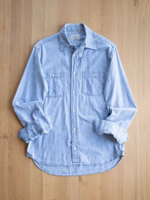 French Workers Shirt, size S - Snygg ljusblå jeansskjorta i bomull med klassisk krage och två bröstfickor. Skjortan har långa ärmar och vita knappar framtill. Perfekt för en avslappnad och trendig look.