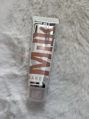 Milk Makeup Bionic Glow Highlighter - Highlighter från Milk Makeup i tubformat med text i kopparfärg. Produkten heter Bionic Glow och ger ett naturligt glow till huden. Tuben är vit med grafiska detaljer och har ett genomskinligt lock. Perfekt för dig som vill ha en fräsch och glansig finish. Använd 1 gång.