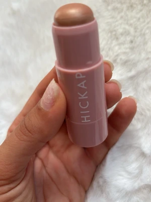 Hickap Pure Bronze Highlighter stick - Krämig highlighter i stickformat från Hickap i nyansen Pure Bronze. Kommer i en ljusrosa hylsa och ger en bronzig, skimrande finish. Perfekt för att framhäva kindben, näsrygg och amorbåge. Enkel att applicera direkt på huden. Provad 1 gång.
