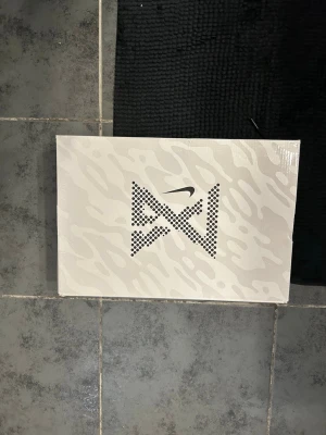 Svarta Nike basketskor med blå detaljer - Säljer ett par svarta Nike basketskor med blå detaljer och vita swoosh-loggor. Skorna har mesh-överdel för bra ventilation, snörning och vadderad insida i blått. Snygg design med röda accenter och slitstark sula för bra grepp på planen.