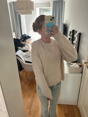 Beige oversized stickad tröja - Mysig beige stickad tröja med rund hals och långa ärmar. Tröjan har en avslappnad, oversized passform och ribbade muddar vid ärmslut och nederkant. Perfekt för lager på lager och chill dagar.