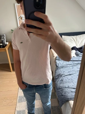 Rosa Lacoste piké  - Säljer en ljusrosa pikétröja från Lacoste med klassisk krage och två knappar framtill i storlek S (16år) . Tröjan har korta ärmar och den ikoniska krokodilloggan på bröstet. Självklart kan jag gå ned  lite i pris vid snabb affär, ställ gärna frågor är bara att skriva !