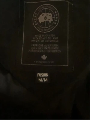 Svart dunjacka med huva - Säljer en svart dunjacka från Canada Goose med huva och klassisk patch på ärmen. Jackan har en puffig design och är perfekt för kalla vinterdagar. Stängs med dragkedja och har en stilren look som funkar till det mesta.