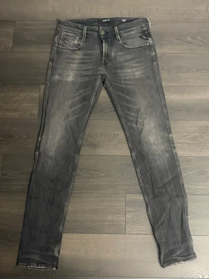 Mörkgrå jeans från replay  - Snygga grå slim fit jeans med slitna detaljer och tvättade partier framtill och baktill. Klassisk femficksmodell med dragkedja och knapp i midjan. Finns en liten defekt på jeansen som man kan se på sista bilden, sitter under vänster ficka. 