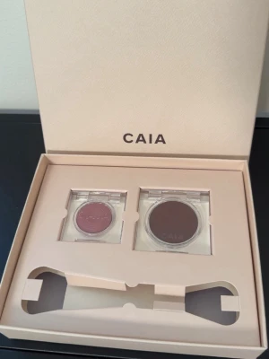 2 st CAIA blush FLUSH RUSH DUO BLUSH GIFT BOX - En snabb väg till lyster. Flush Rush samlar två kalltonade blush som ger energi till kinderna. Electric Fig Glow Blush – ny nyans i nytt reseformat – möter Lady Plum i vår Soft Melt-formula. Det som inte medföljer i giftboxen är mini duo sminkborsten. Båda blushen är helt nya och har inte tagits ut ur boxen. Baksidan på boxen har skavts av lite i färgen när boxen skulle öppnas (se bild 4). 