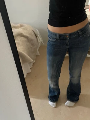 Blå bootcut jeans med låg midja - Säljer ett par blå bootcut jeans med låg midja. Jeansen har klassisk femficksmodell, dragkedja och knapp i gylfen. Materialet är denim i bomull med lite stretch för skön passform. Perfekta till sneakers eller boots. (är storlek 28/34 men uppsydda typ 2cm i längden, så mer som en 28/32!) har lite slit allra längst ner men inget som syns  💕💕