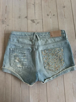 Jeans Shorts - As coola unika jeans shorts med nitar och slitningar. Är lowwaist/midwaist. 