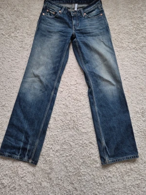 Weekday arrow jeans W25 L30 - Klassiska blå jeans med rak passform och snygga slitningar på framsidan. Jeansen har fem fickor, gylf med dragkedja och kontrastsömmar.