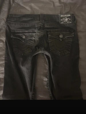 Svarta True Religion jeans - Säljer ett par svarta jeans från True Religion med ikoniska fickor, säljer pga att dom satt för stort och löst i både midja och lår, pris kan diskuteras!!