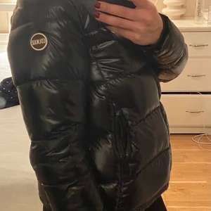 Colmar dunjacka dam - Dunjacka för damer i ett svart glansigt material i storlek s/36. Jackan är inköpt på Jackie förra året. Använd endast ett fåtal gånger så jackan är i nyskick. Pris 3500kr 