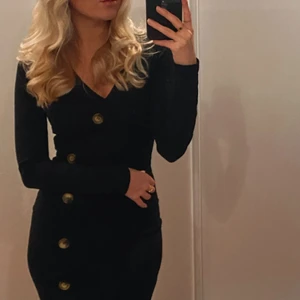 Svart långklänning med knappar - Svart långklänning med bruna knappar! De två nedersta knapparna går att knäppa upp om man vill skapa en slits! Köpt i storlek 34 från h&m Trend! Frakt ingår i pris!