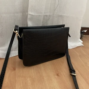 Liten svart väska  - Säljer en liten svart väska i skinnimitation. Supersöt och rymmer förvånansvärt mycket! Mobil, pengar, kort, läppglans, smink osv… väldigt simpel och basic och passar till allt! ☺️ köptes för 250kr har jag för mig men säljer för 75 ❤️