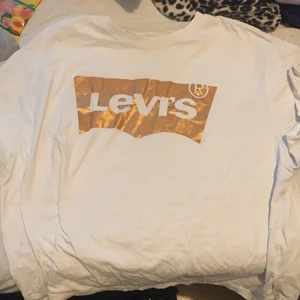En vit Levis med guld runt texten - En vit Levis tröja med guld runt texten Levis använd 1 gpng på grund av att den inte passar stilen jag har just nu L men folk i storlek s kan använda