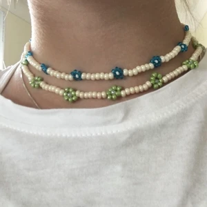 Pärlhalsband med blommor  - Säljer dessa fina pärlhalsband med blommor som jag gjort själv 🥰 finns i grönt och blått 💚💙 ett halsband kostar 20 kr och två stycken 30 kr det blå halsbandet är 34 cm långt och det gröna 37 cm