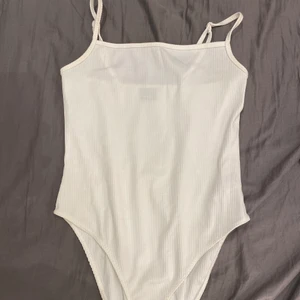 Vit linne bodysuit - Jätte fin tajt linne bodysuit i ribbat material, köpt på gina tricot. Säljs eftersom den inte kommer till användning längre, då den knappt är använd. Skriv gärna om ni är intresserade eller har frågor/ vill se mera bilder på plaget, ex hur det sitter på osv❤️ storlek L men skulle säga att den även passar M.