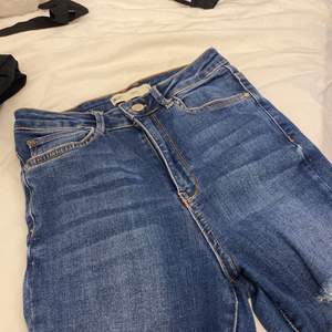 Blåa skinny jeans från Gina med tre hål vid benen 