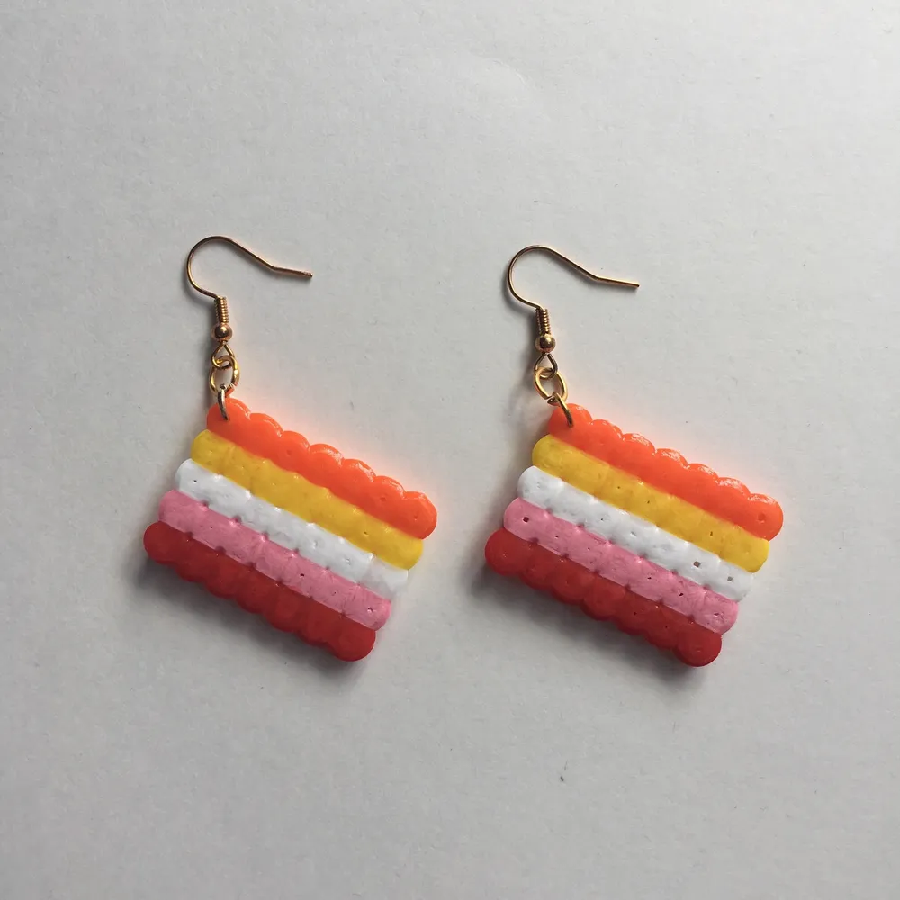 Egengjorda nickelfria örhängen av lesbiska flaggan 🧡💛🤍💖❤️ Andra prideflaggor finns på min sida!. Accessoarer.