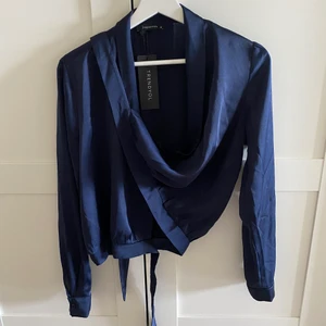 Omlottblus från NAKD oanvänd  - Oanvänd mörkblå omlottblus i siden-imitation. Storlek 38, passar S-M. Pris 90kr 