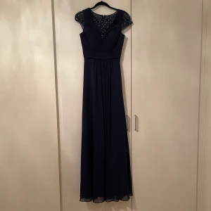 Mörkblå balklänning i strl 38 - Jätte snygg designer klänning i mörkblå färg, som man kan ha både på bal och bröllop, men även på andra tillfällen. Sitter jätte fint runt midjan och har den perfekta längden. Har använt den en gång några timmar. Säljer pga garberob rensing.