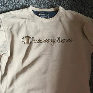 Champion Tröja   - Champion tröja. Beige med guld/svart tryck. Köparen står för frakt 