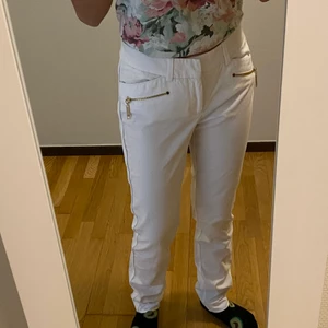 Vita low waist  - Vita low waist byxor med guld-detaljer från Lindex i storlek 36-38. Använda fåtal gånger, men kommer aldrig till användning längre. Fint skick och sitter bra. Jag är 165 och dom är lite smått långa.