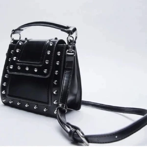 Zara väska - Säljer denna fina väska från zara. Dock utan ”handtaget” (se bild 2). Jättefint skick, inga repor/fläckar och alla nitar finns kvar🌸 skriv om ni har några frågor💕 OBS axelbandet är kvar. Priset är exklusive frakt