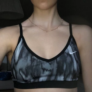 Nike sporttopp strl. S - Vit- och gråmönstrad stoprttopp från Nike strl. S. Inte vadderad. Superfin!! Något nopprig på banden i bak. Gratis frakt.