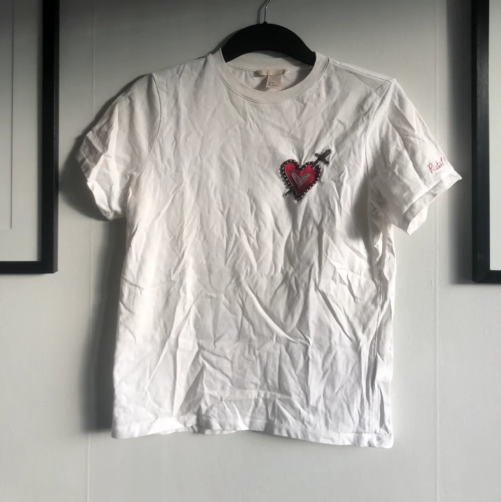 Säljer en vit t-shirt från HM med ett hjärta av pärlor, paljetter och broderi. Skick: använd men hel! Material: 100% bomull. 🌟. T-shirts.