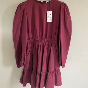 Vinröd klänning - En vacker vinröd klänning med puffärm. Helt oanvänd och märket är NAKD. Storlek 40 men passar även för en i strl 38. Rymlig i modellen men faller snyggt mot kroppen där det blir ”luftigt”. Knälång.   Jag skickar klänningen med posten enligt postens priser. 