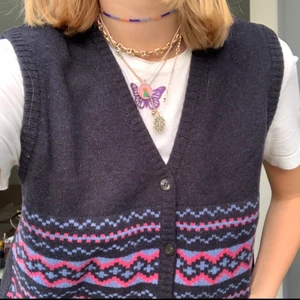 Trendig stickad väst - Cool och trendig stickad mörkblå väst med mönster framtill i olika förger ( mönstret fortsätter inte baktill). Den har knappar i fram så man kan ha den uppknäppt om man vill. Köpt second hand och i mycket bra skick. Det står ingen storlek, men jag skulle säga att det är en M och att den är lite oversized i modellen.😊