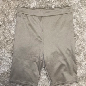 Grå/beige cykelbyxor strl l - Grå/beigea cykelbyxor i glansigt material. Aldrig använda för att de är för stora, men modellen är jättefin