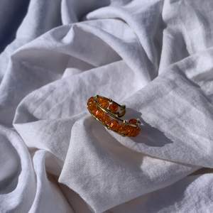Handgjord ring med orangea pärlor, och guldpläterad koppartråd. Den är justerbar.