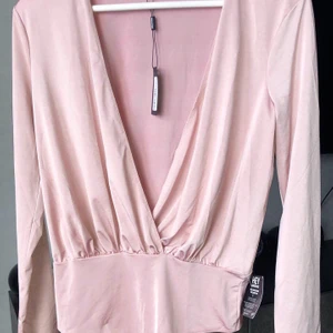 Body - Fin body/omlott blus i storlek M. Lappar kvar, har dock en liten skada (se bild) däremot syns det otroligt lite på baksidan! 