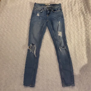 Jeans från Gina tricot strl W.24 - Tighta jeans med hål från Gina tricot i storlek W.24, modell Kristen 💜💜 Lågmidjade. Jeansen är i mycket fint skick och är använda enstaka gånger, säljer då jag inte kan ha dessa längre. Samfraktar gärna med andra plagg och betalning sker via Swish <33