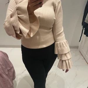 Ribbad tröja. - Ribbad tight rosa tröja med volanger längst ner på båda armarna.