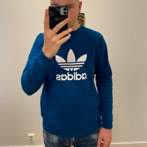 Adidas tröja - Blå Adidas tröja/sweatshirt i bra skick. Storlek S men sitter som en M. Pytteliten fläck på magen som knappt syns.