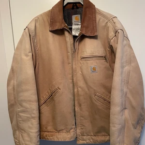 Carhartt Detroit-jacka Made in USA - Säljer en riktigt fin vintage Detroit-jacka från Carhartt. Perfekt fade från den från början klassiska duck brown.  -J01 BRN Made in USA!   -Kontrasterande manchesterkrage.  -Dragkedjor fungerar perfekt.  -Filtfodrad med nylonfodring i ärmar.  -Storlek är 44 vilket från Carhartts storlekstabell på hemsidan motsvarar L.  -Inga hål eller revor i tyget, den lilla slitningen som finns är nere vid ärmsluten.  Finns för avhämtning i Nyköping eller skickas mot fraktkostnad.  /Mattias