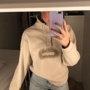 Beige fleece - Beige fleecetröja med dragkedja halvvägs ned, litet tryck på magen och som ”lappar” för axlarna. Köpt på humana i höstas men knappt använd! Storlek L men skulle säga något mindre