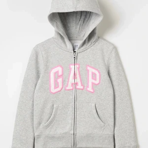 Tröja med dragkedja från märket GAP - GAP Kids i storlek XL på barn för cirka 11-13 år, köpt för ett halvårsen och använd fåtal gånger. I färgen grå med stora bokstäver av rosa o vit. 