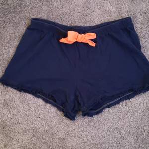 Marinblå pyjamas shorts med neon orange rosett. I väldigt fint skick och knappt använda. Stretchiga i både midjan och på benen. Storlek: 158/164